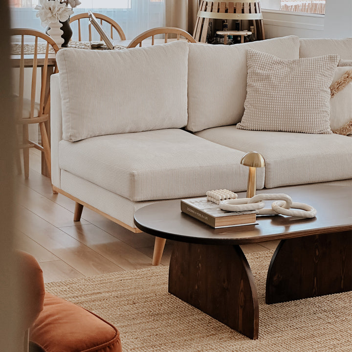 altin sarisi lambali, beyaz dekorla tamamlanmis ladin ahsap sehpa ve dogal dokulu haliya sahip sik Japandi tarzı oturma odasi