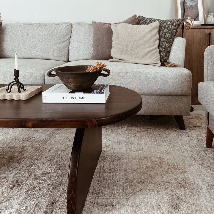 ahsap orta sehpa krem rengi kanepe ve sicak bir atmosfer yaratan yumusak aydinlatma ile sik ladin Japandi oturma odasi