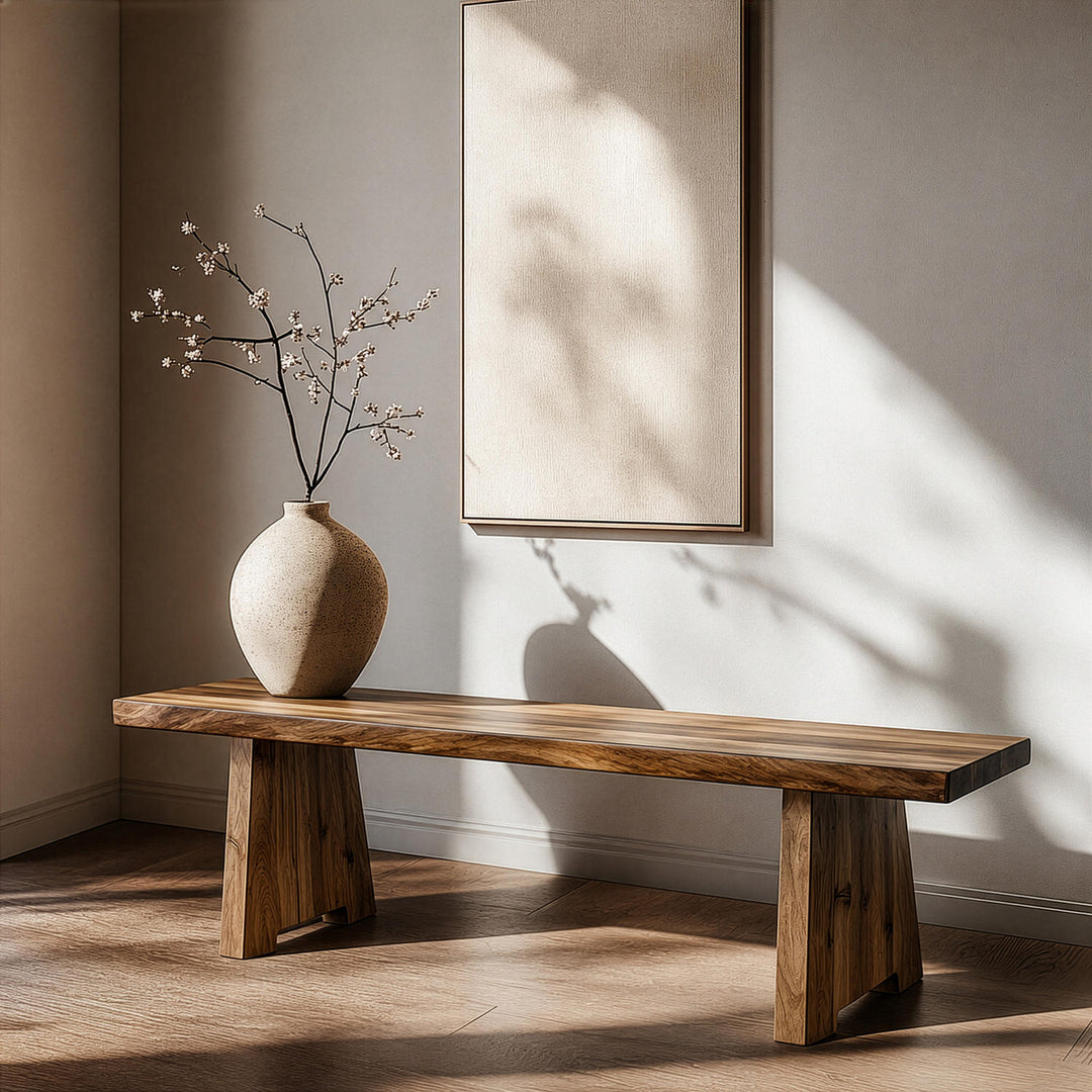 Kalın kütük yapılı ceviz ağacından ahşap bench, üzerinde minimalist küresel bir seramik vazo ile sakin bir iç mekanda sergileniyor.