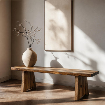Kalın kütük yapılı ceviz ağacından ahşap bench, üzerinde minimalist küresel bir seramik vazo ile sakin bir iç mekanda sergileniyor.