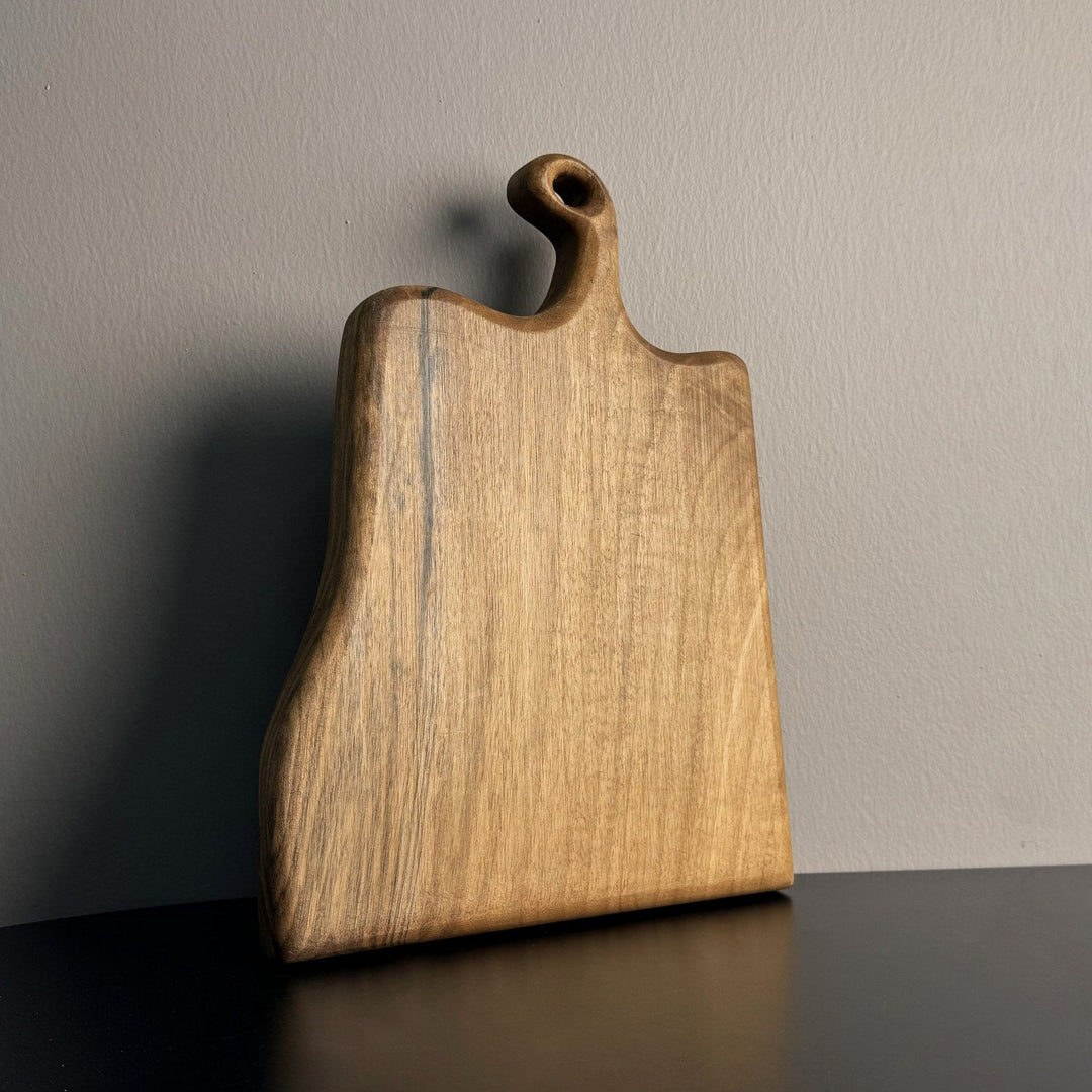 dogal masif ceviz ahsap kesme tahtasi dikey olarak yerlestirilmis sadeligiyle dikkat ceken dogal dokusu belirgin ve ozenle sekillendirilmis tutma yeri vornom