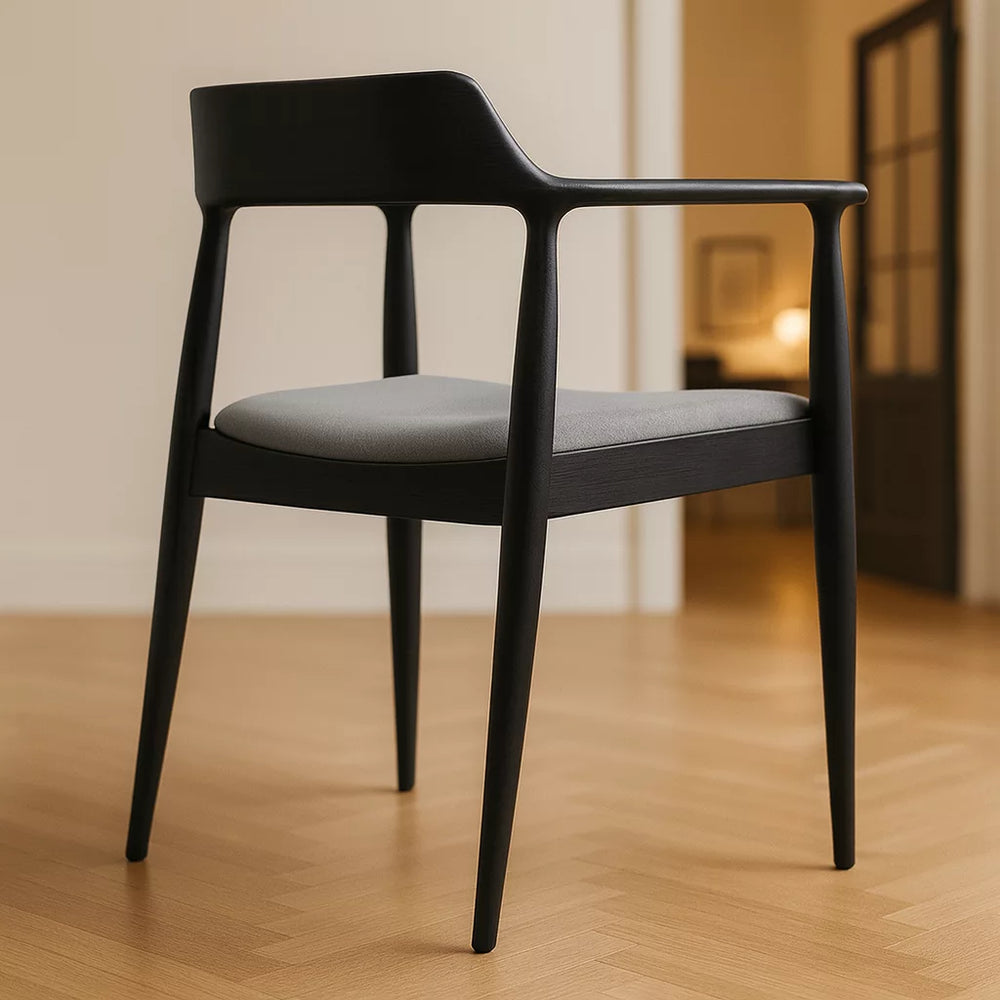 Siyah ahşap yemek sandalyesi, üzerinde gri bir yastık ile birlikte. İskandinav stiline uygun bir tasarım.
