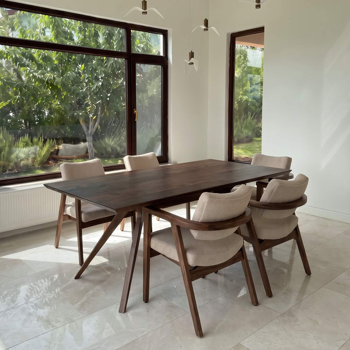 Vigo natural solid walnut dining table styled with modern upholstered armchairs in a bright dining room